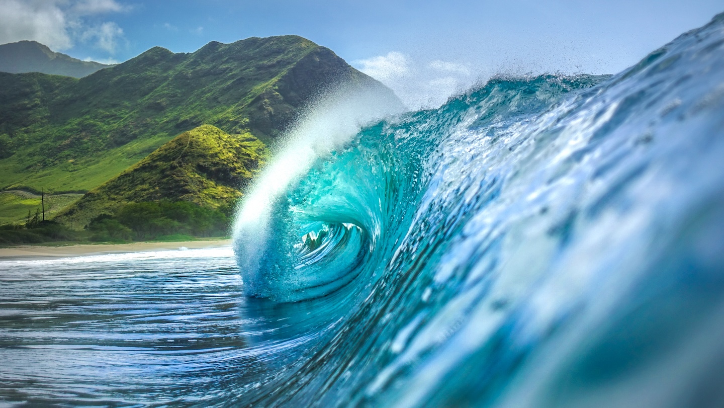Crystal clear Hawaiian wave with green mountains on Big Island