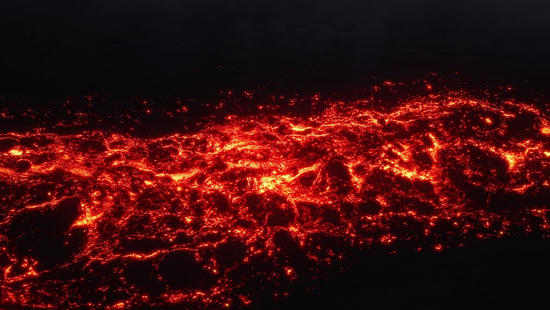 Glowing river of molten lava flowing across the dark Kilauea crater floor at night